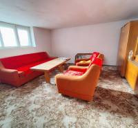 Living room in a family house with an orange sofa, wooden table, and display cabinet.