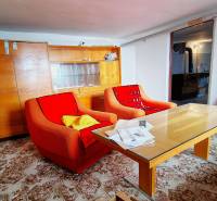 Living room in a family house with older armchairs, a table, and a glass cabinet.