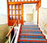 A staircase in a family house with colorful tiles and a wooden railing.