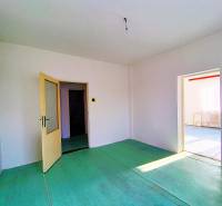 The interior of a family house with open doors, white walls, and a green floor.