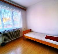 Single room with a bed and a window, wooden decor flooring, in a family house.
