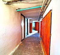 A hallway of a family house with wooden doors and exposed pipes.