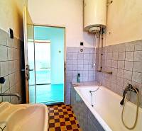 A bathroom in a family house with a bathtub, a sink, and a checkered tile floor.