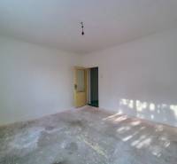 Empty room with white walls and a concrete floor in a family house.