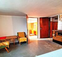 A room in a family house with armchairs, a table, and an old stove.