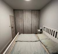 A bright bedroom in a two-room apartment with a spacious bed and a wardrobe with a wooden decor.