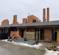 Construction of a family house in Višňové, Višňové, made of red brick, with piles of wood.