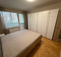 Bedroom in a three-room apartment with a wooden decor floor and a large built-in wardrobe.