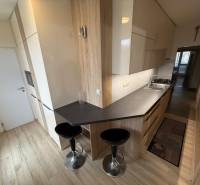 A kitchen in a 3-room apartment with a wooden decor floor and a dining counter.