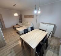 Living room with wood-patterned flooring, a sofa, and a table in a three-room apartment.