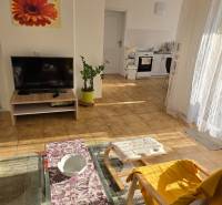 Living room in a family house with a sofa, television, and a view of the kitchen.