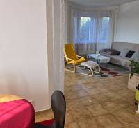 Living room in a family house with a window, a yellow armchair, and a table.