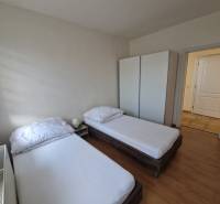 A room in a family house with two beds, a wardrobe, and a floor with a wooden decor.