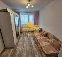 A room in a 3-room apartment with a sofa, a wardrobe, and a floor with a wooden decor.