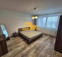 Bedroom in a 3-room apartment with a bed, mirror, and floor with a wooden decor.