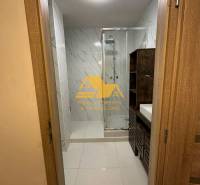 Bathroom with a shower and a sink in a 2-room apartment, with tiles in light tones.