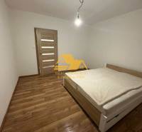 Bedroom in a 2-room apartment with a bed, wooden floor decor, and simple lighting.