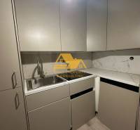 A kitchen in a 2-room apartment with a marble countertop and gray cabinets.