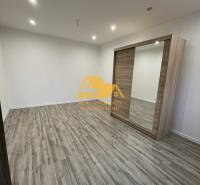 Interior of a 1-room apartment with a wood-patterned floor and a built-in wardrobe.