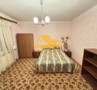 Bedroom in a family house with carpet and furniture, soft pink wallpaper.
