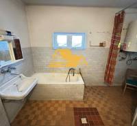 A bathroom in a family house with a bathtub, a sink, and a boiler.