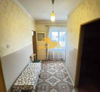 A hallway in a family house with carpet decor and a table, a window at the end of the room.