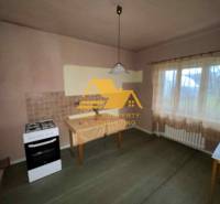 A kitchen in a family house with a stove, table, curtain, and light wall decor.