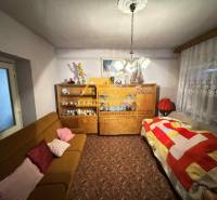 Living room in a family house with a carpet, sofa, and a cabinet with porcelain.