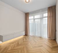 Living room in a two-room apartment with a wooden decor floor and white furniture.