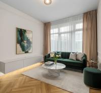 Living room with a green sofa, decorative table, and wood-patterned flooring.