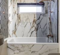 A bathroom in a 2-room apartment with designer tiles and a bathtub in a marble decor.