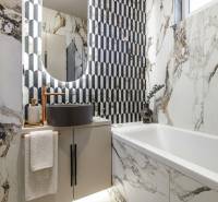 A bathroom in a 2-room apartment with marble tiles and a modern sink.