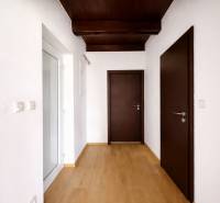 A hallway in a family house with a wooden decor floor and dark brown doors.