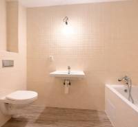 A bathroom in a family house with a bathtub, a sink, and a wooden decor floor.