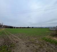 Commercial land in Pruské with power lines and green lawn under an overcast sky.