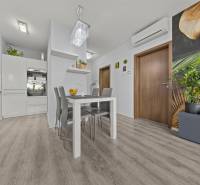 Dining area with a white table and gray chairs in a 2-room apartment, floor with wood decor.