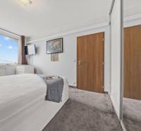 A bright bedroom with a bed, a large window, and a wardrobe in a 2-room apartment.