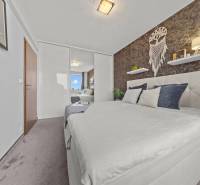 Bedroom in a 2-room apartment with a double bed, mirrored wardrobe, and wall decorations.