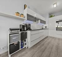 A kitchen in a 2-room apartment with white cabinets and a wood-patterned floor.