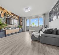 Living room with a comfortable sofa, wallpaper with a plant motif, and a wooden decor floor.