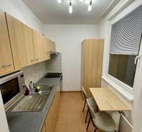A kitchen in a studio apartment with a minimalist table and light furniture.