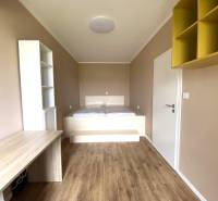 A room in a 3-room apartment with a wooden decor floor and a built-in desk.