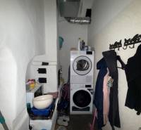 Laundry room with a washing machine, dryer, coats, and storage space in commercial premises.