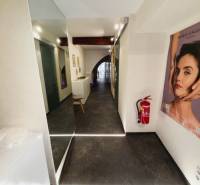 A corridor of commercial premises with a poster, wooden decor flooring, and a fire extinguisher.