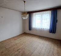 A room in a family house with a wooden decor floor, curtains, and a chandelier.