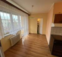 A kitchen with a wood-patterned floor, curtains, and a radiator in a 3-room apartment.