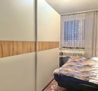 Bedroom in a 2-room apartment with a large wardrobe and a window with decorative curtains.