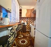 A kitchen in a 2-room apartment with a decorative rug, stools, and a tiled wall.