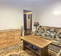 Living room in a two-room apartment with a wooden sideboard and a patterned carpet.