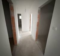 A hallway in a family house with white walls and unfinished doorways.